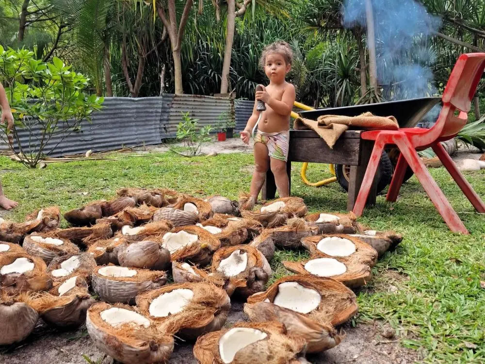 Mica's daugther in front of a bunch of coconuts on the ground at his home in Bora Bora
