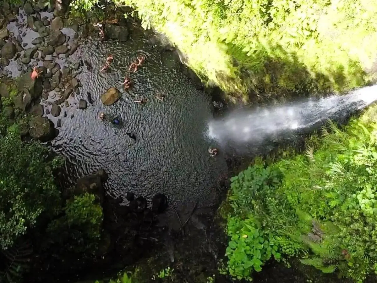 Hikers swimming in a waterfall on the three waterfalls hiking trail in Raiatea