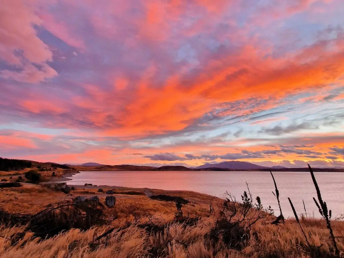 An unreal sunset with pink and purple clouds at Lake Tekapo on a 14-day road trip on New Zealand's South Island