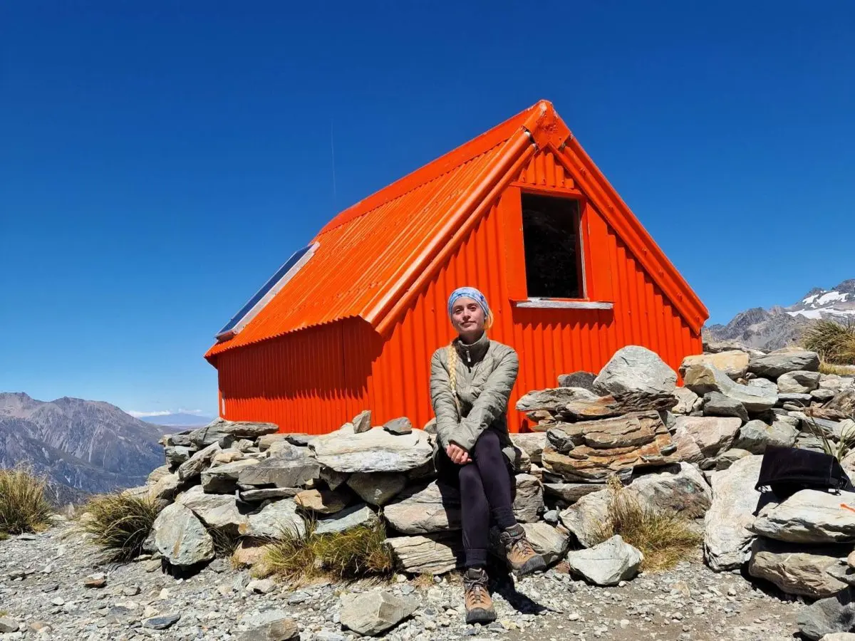 A hiker sitting in front of Sefton Bivvy in Mount Cook National Park, New Zealand