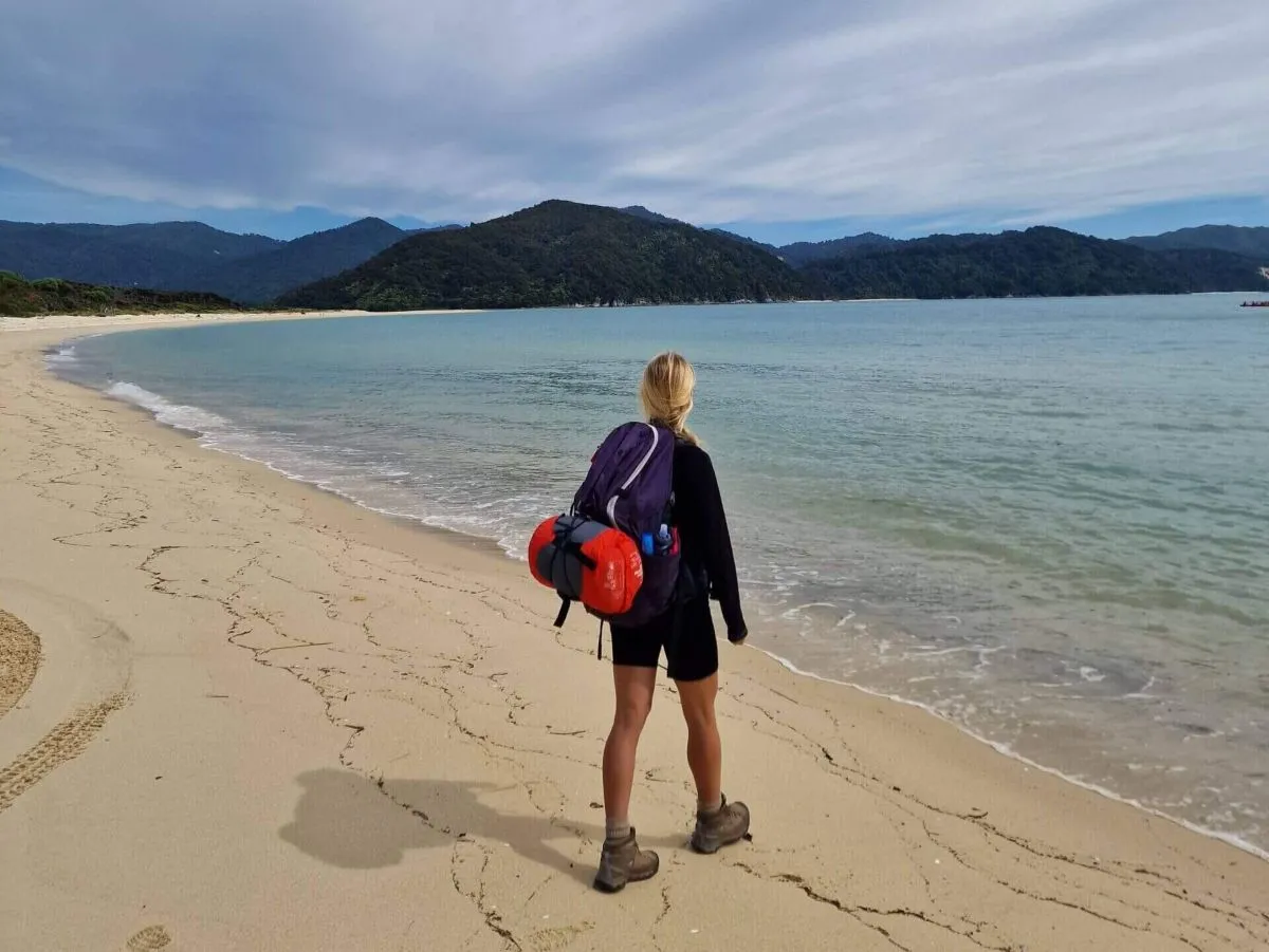 A solo female hiker on the Abel Tasman Coast Track in New Zealand. A hike that is considered very safe for solo female travelers.