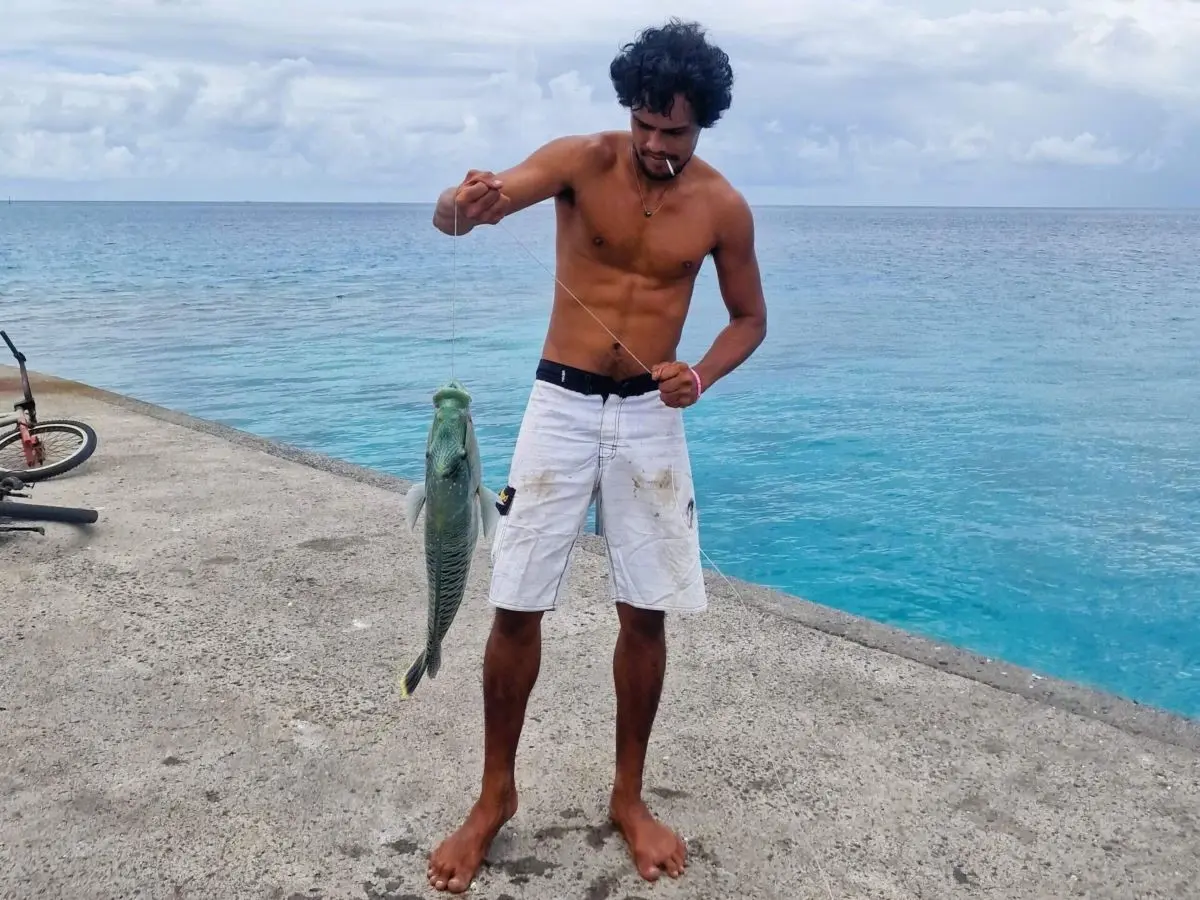 Rainui posing with a green fish, he just caught, on the atoll of Makemo in French Polynesia